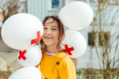 Ein Kind hält Ballone mit dem Logo vom SRK