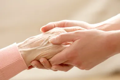 Eine Freiwillige hält die Hand einer älteren Person