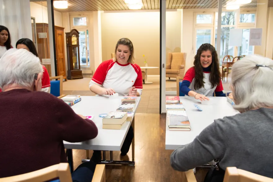 Freiwillige vom Jugendrotkreuz spielen Spiele mit älteren Menschen im Altersheim