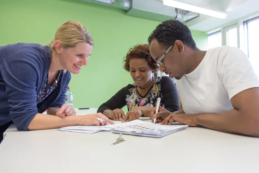 Frau bringt den fremdsprachigen Personen den Wortschatz aus dem Pflegealltag näher