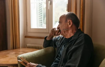 Älterer Mann schaut nachdenklich aus Fenster